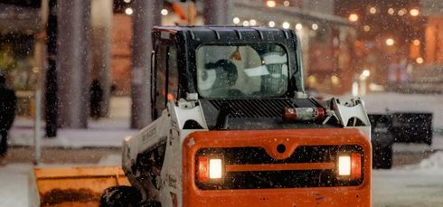 A skid steer pushing snow