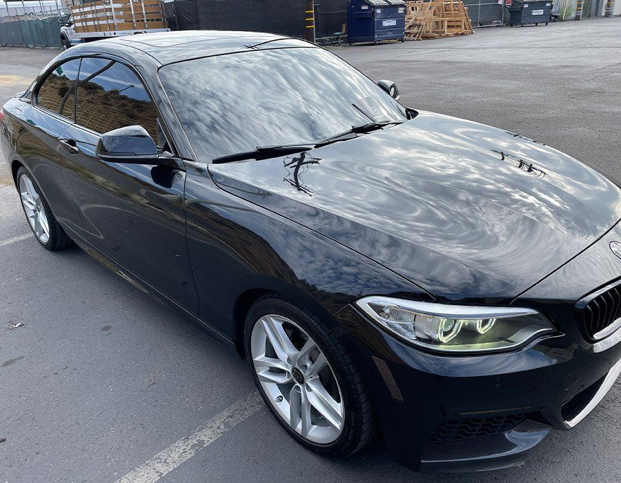 A black bmw is parked in a parking lot.