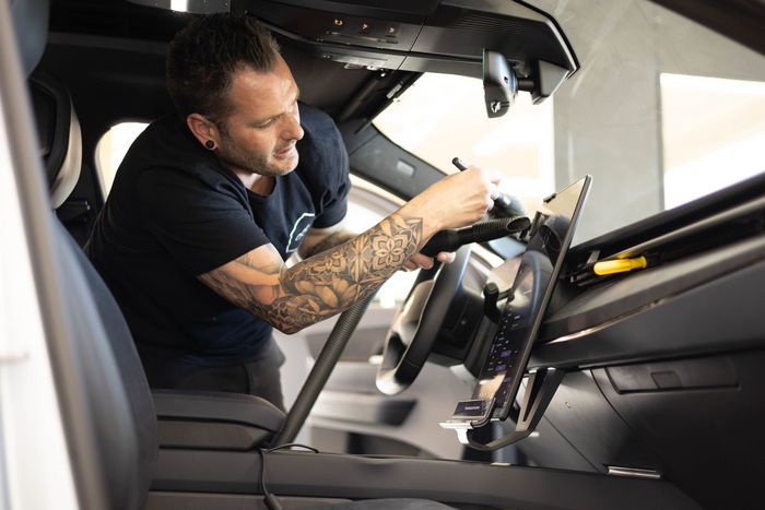 Man in black shirt installing vehicle dashboard screen.