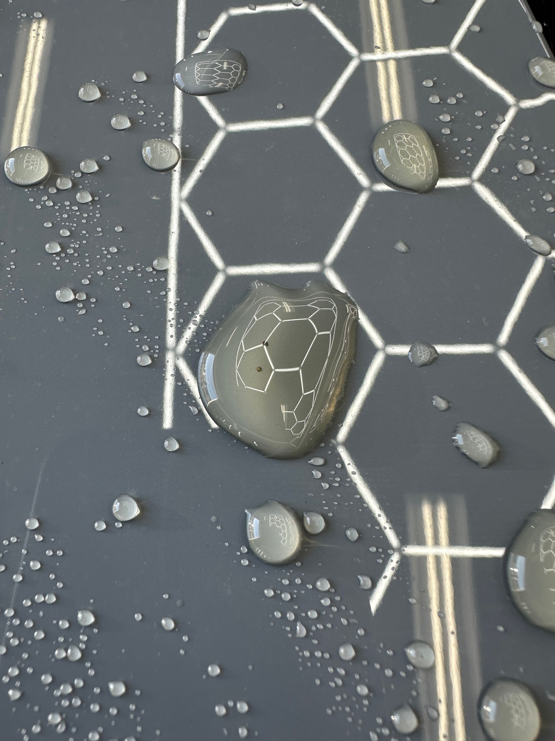 Water drops on a gray surface with a honeycomb pattern