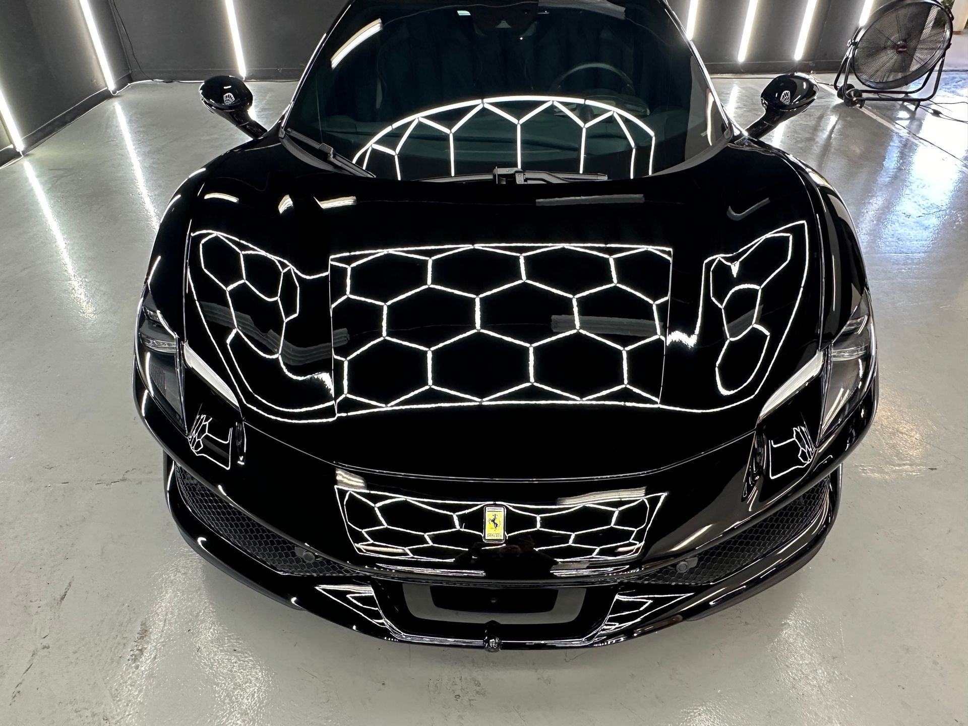 A black sports car is parked in a garage.