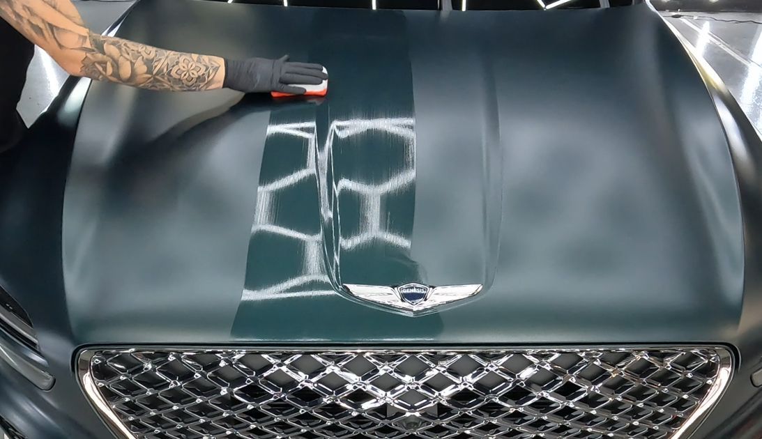 A person is cleaning the hood of a car.