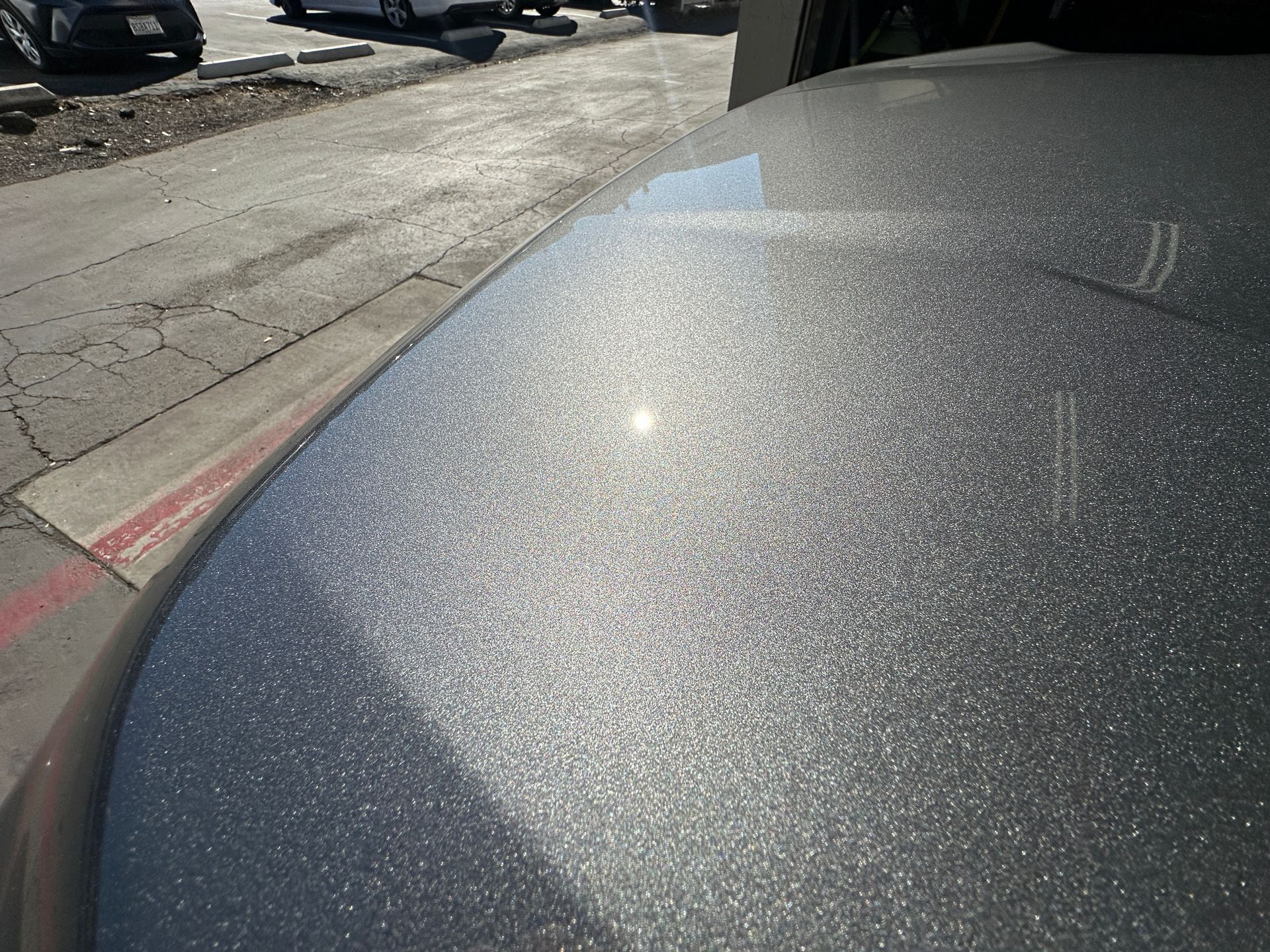 A silver car is parked on the side of the road