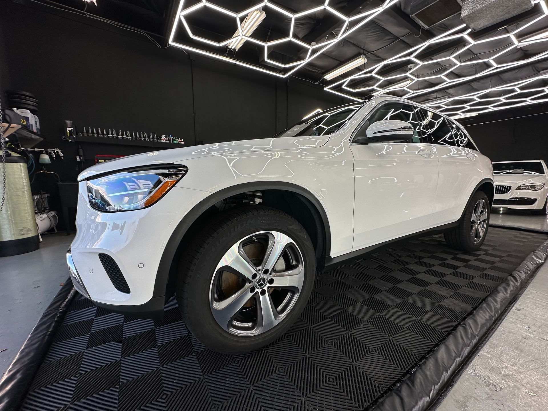 A white suv is parked on a black mat in a showroom.