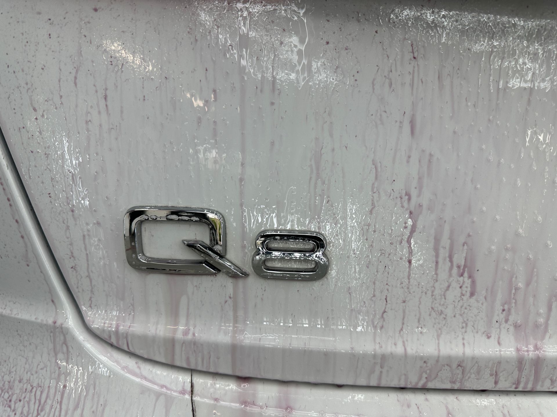 The back of a white car with a q8 emblem on it.