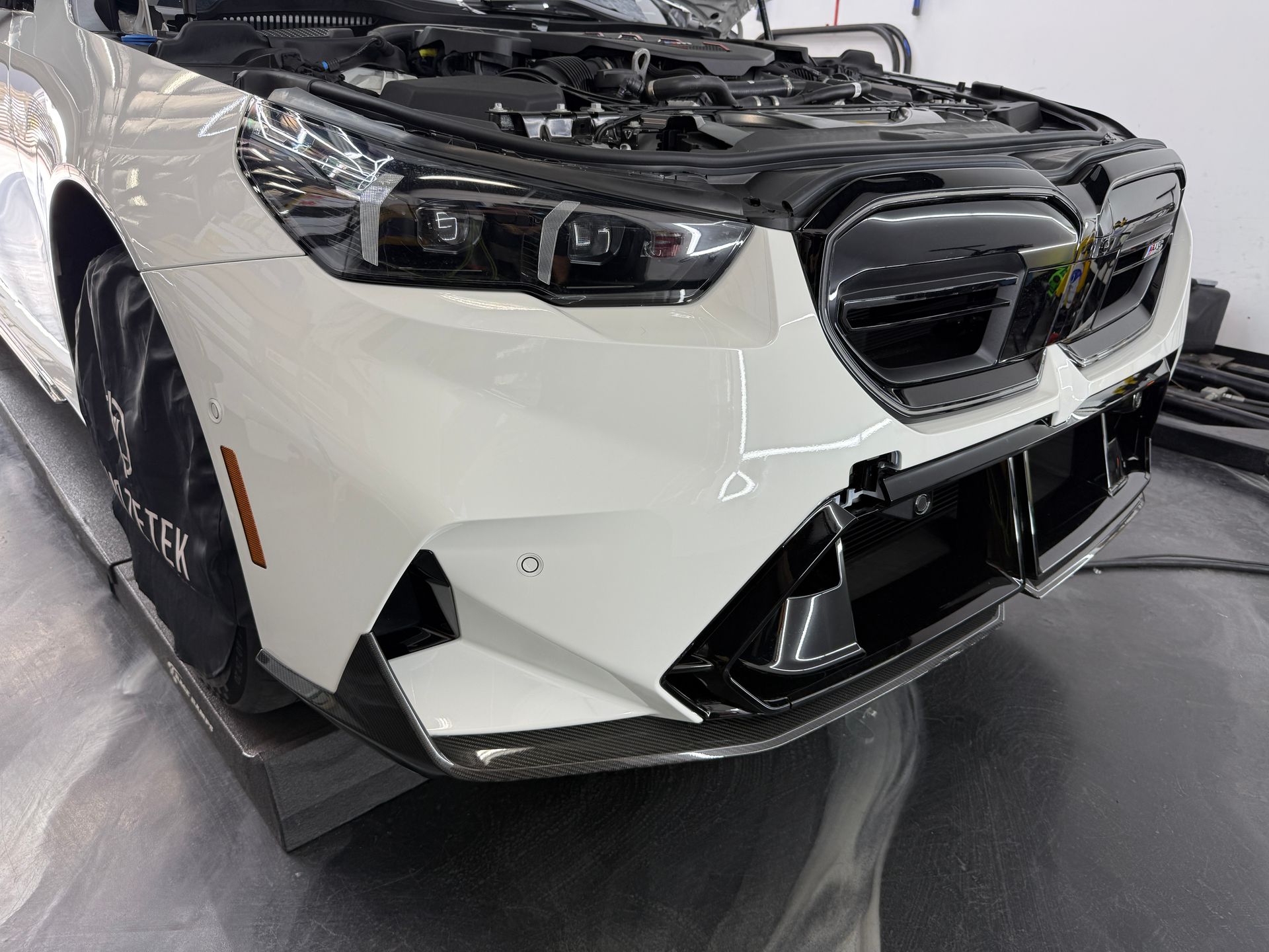 White BMW car with open hood, showing front bumper and grill details.