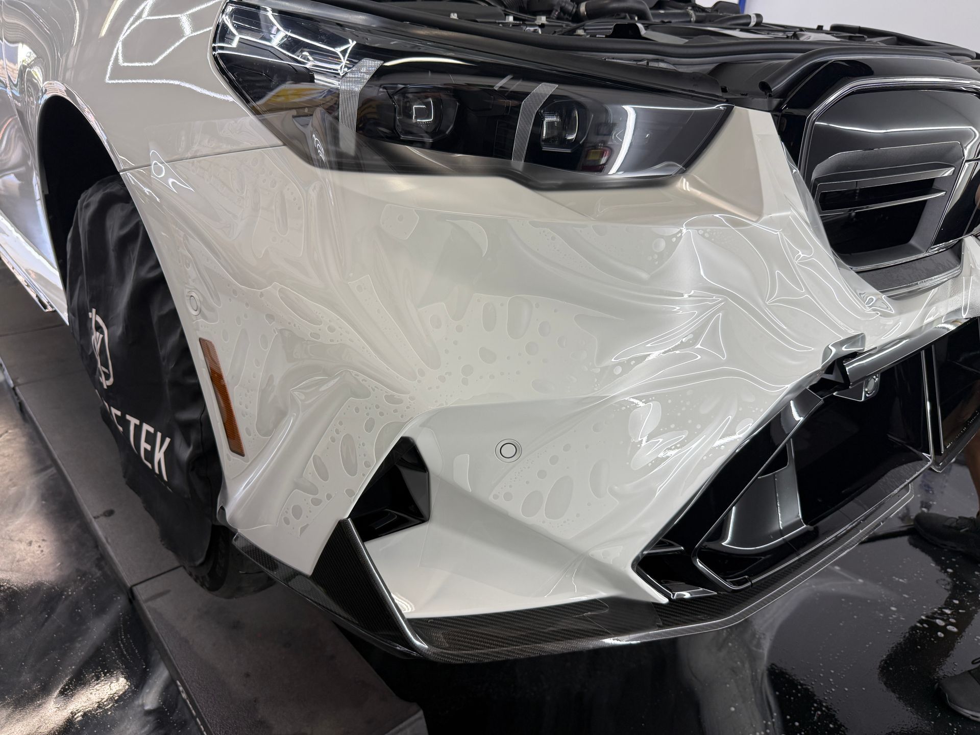 White car's front with black accents, showing swirl pattern on the bumper.