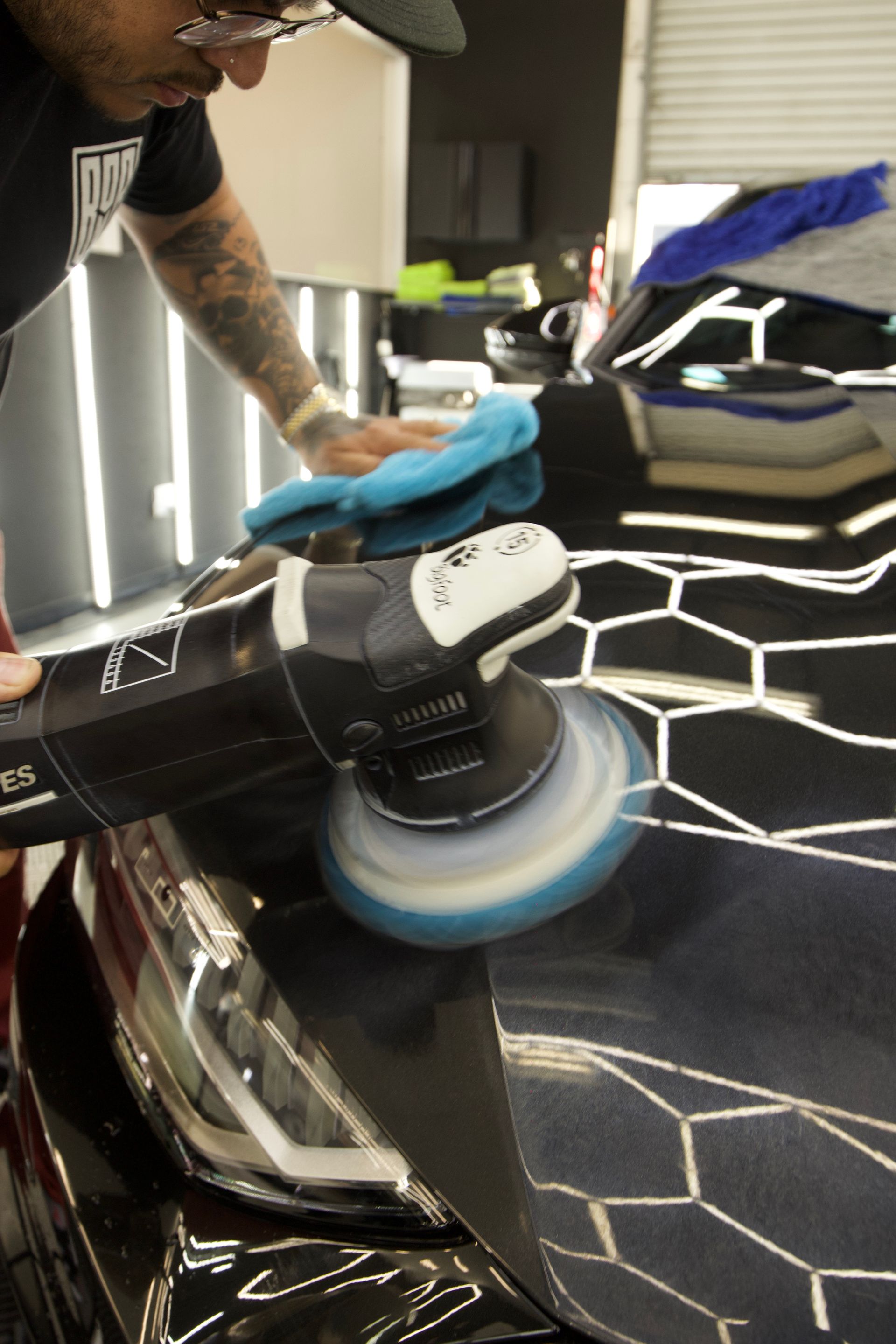 A person is polishing the hood of a white bmw