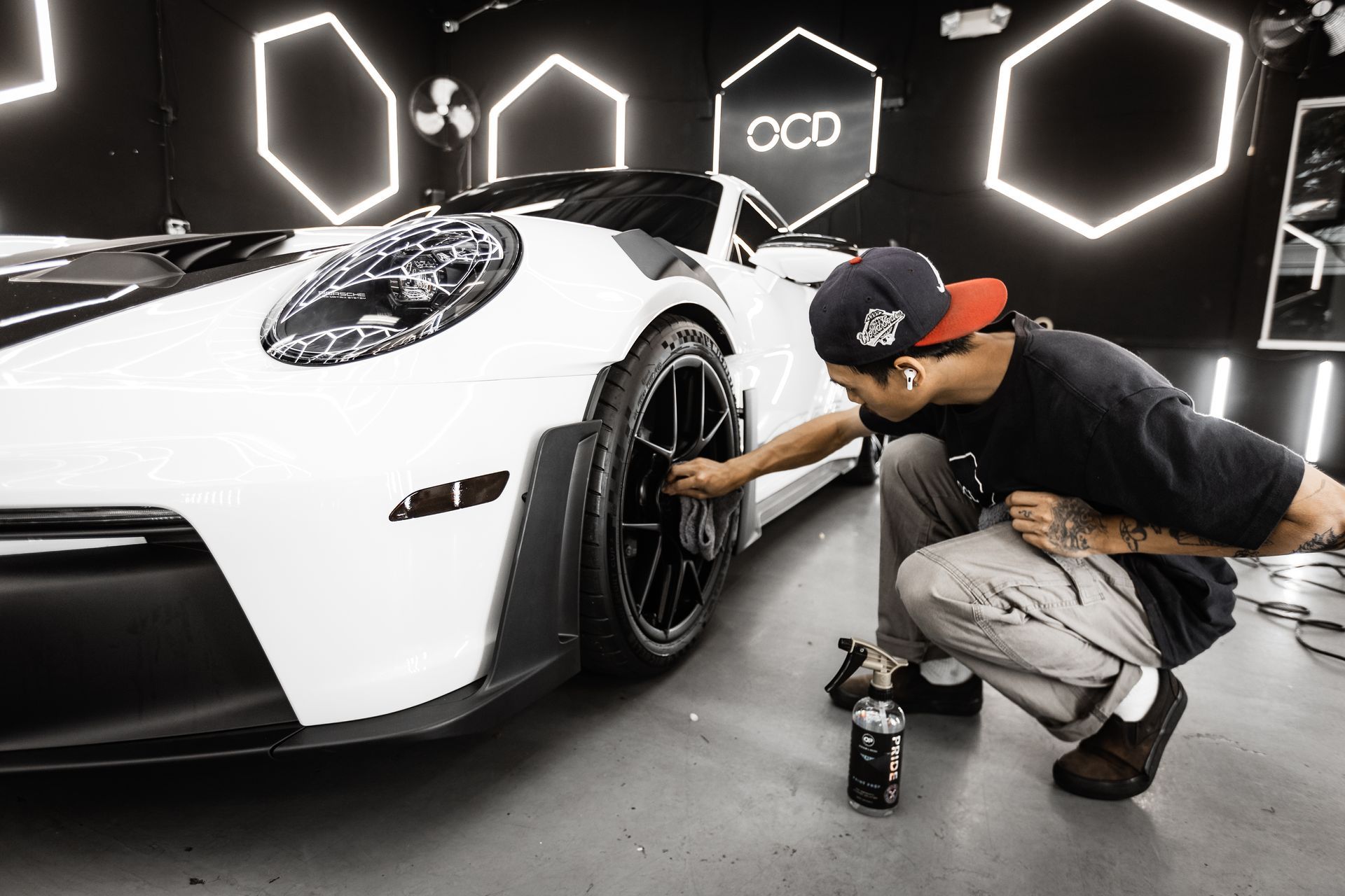 Car wheel being cleaned with foamy soap; white rim, blue BMW logo, black tire, in a car wash.