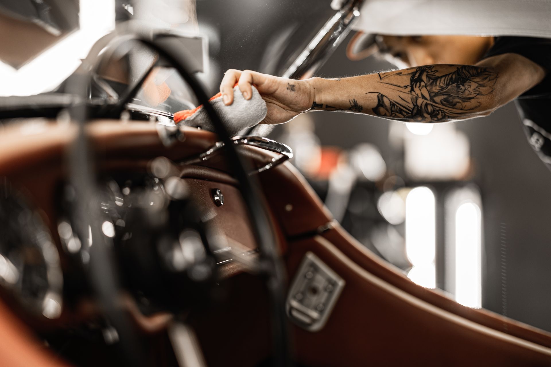 A person is cleaning the interior of a car with a purple cloth.