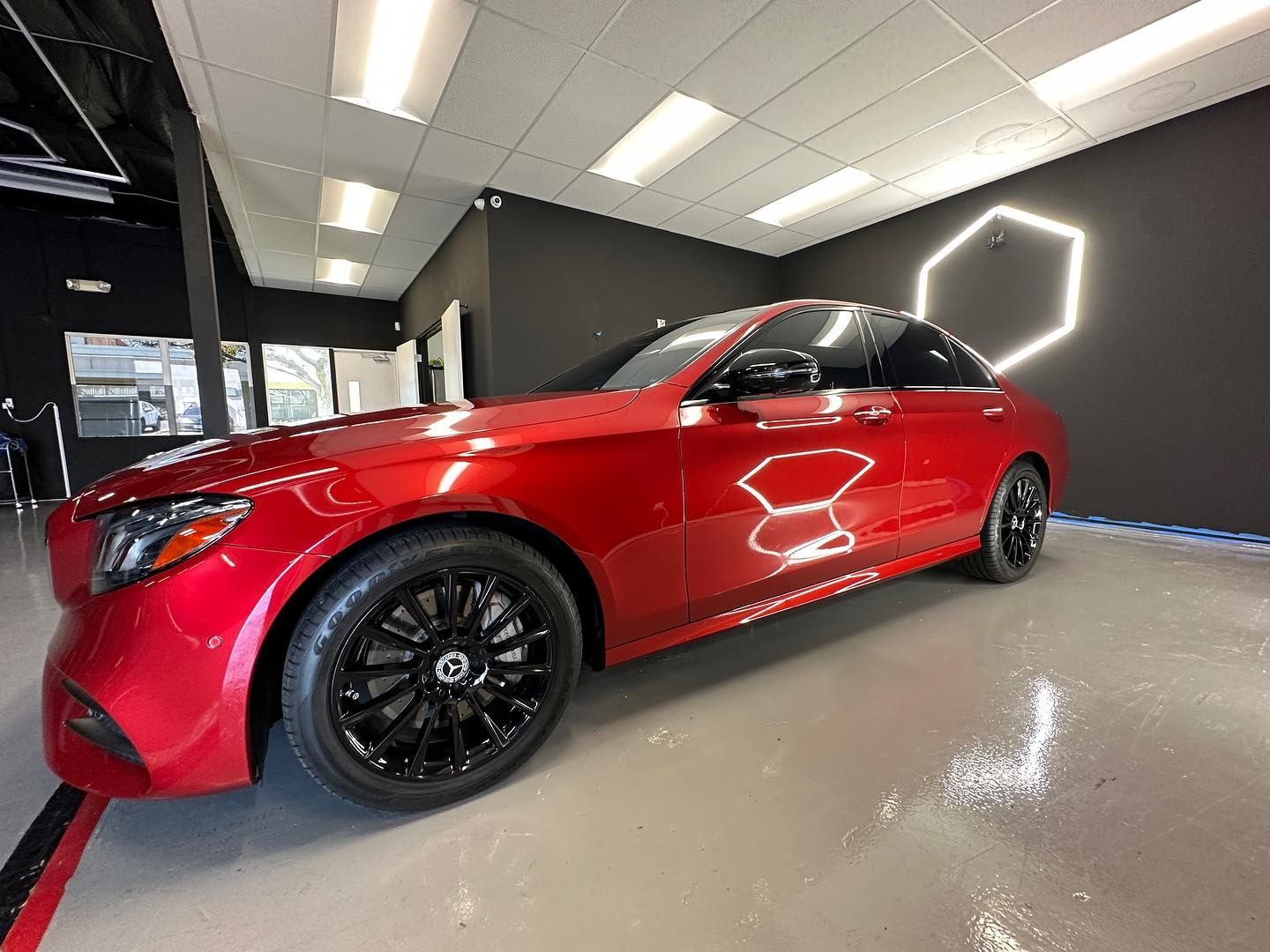 A red car is parked in a garage with black wheels.