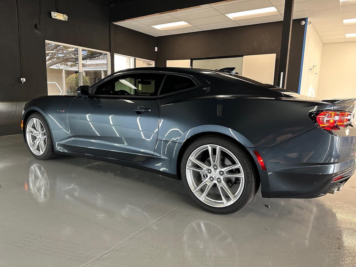 A blue chevrolet camaro is parked in a garage.