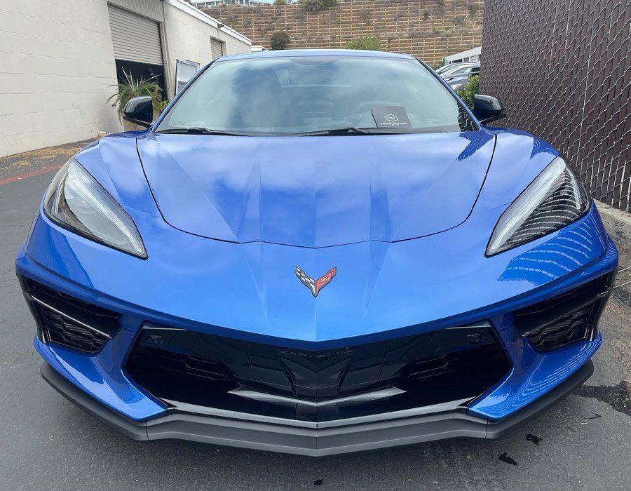 A blue corvette is parked in front of a building.