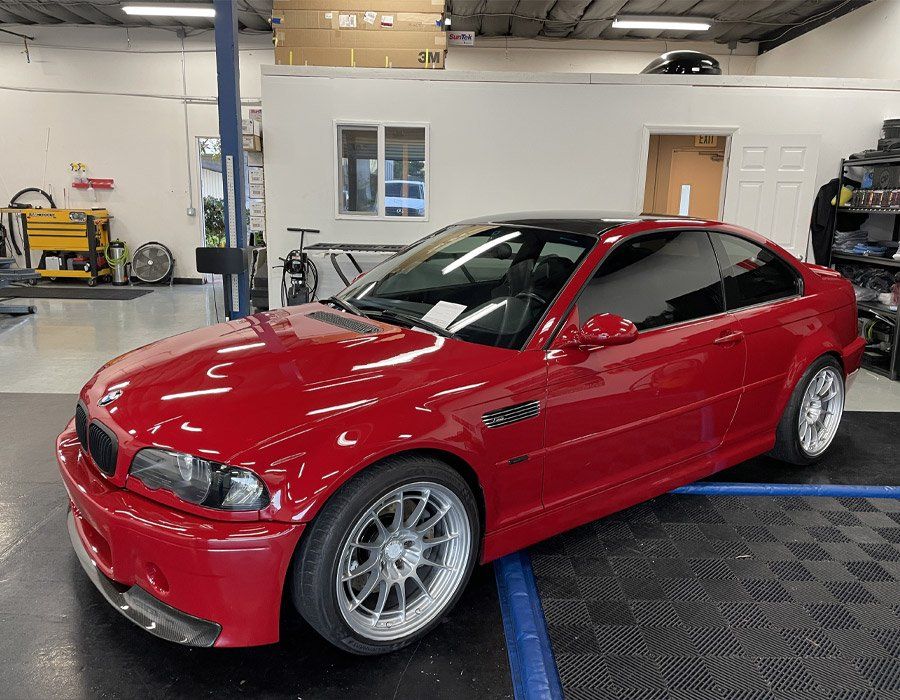 A red bmw m3 is parked in a garage.