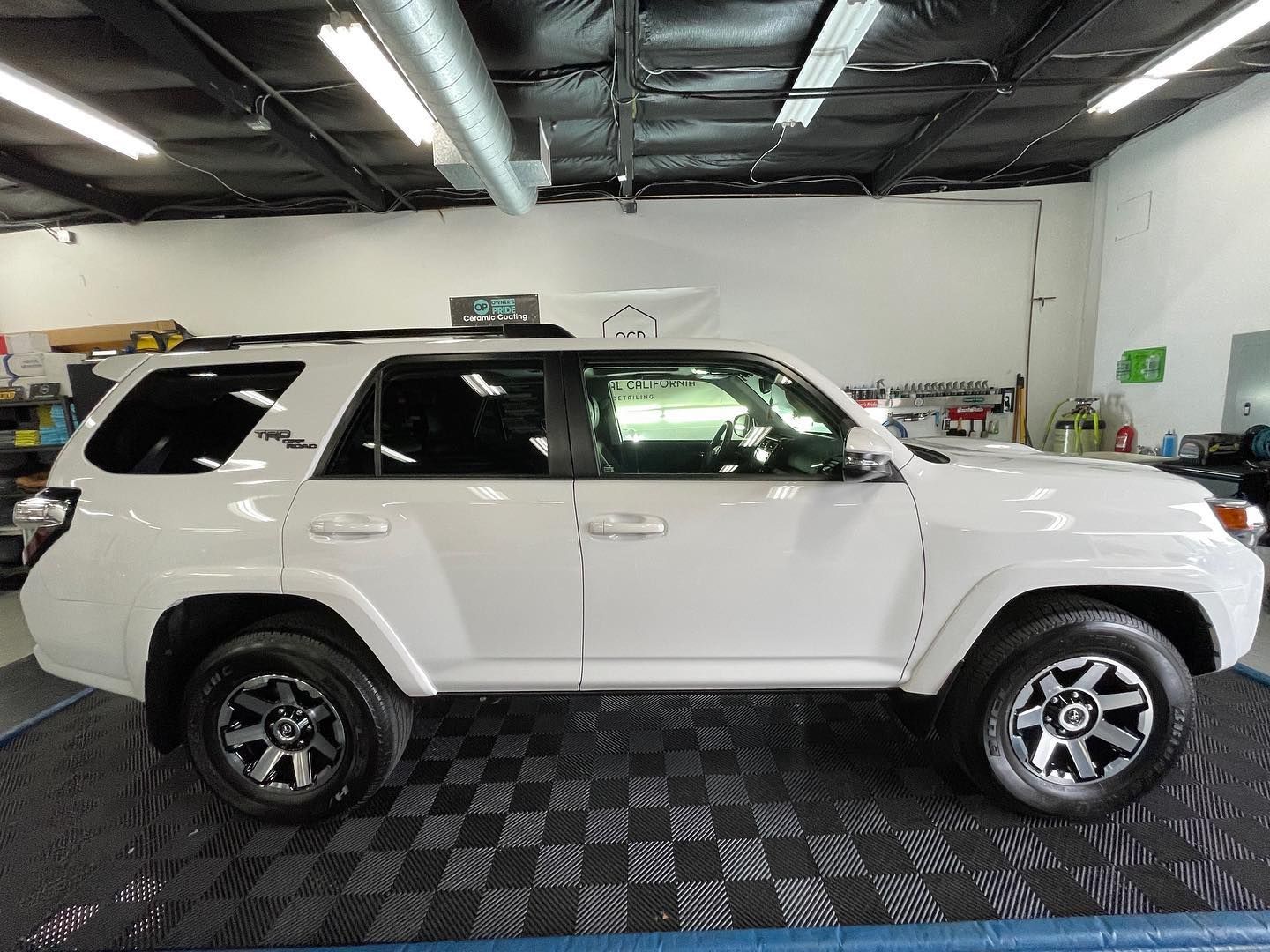 A white toyota 4runner is parked in a garage.