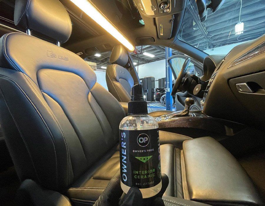 A person is holding a bottle of cleaner in a car.