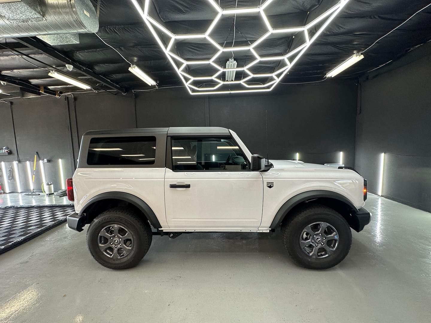 A white ford bronco is parked in a garage.