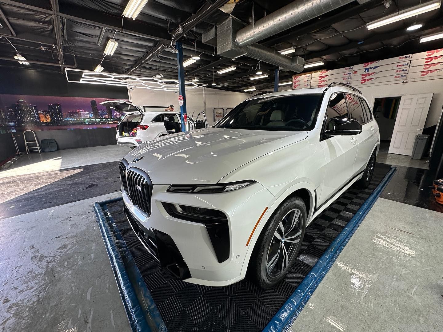 A white bmw x7 is parked in a garage.