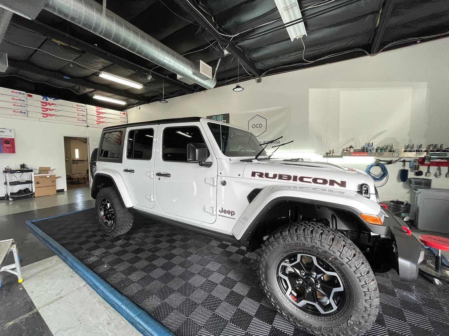 Vehicle fully wrapped in paint protection film in a detailing shop.