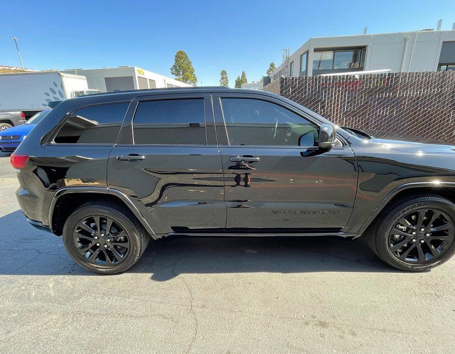 A black jeep grand cherokee is parked in a parking lot.