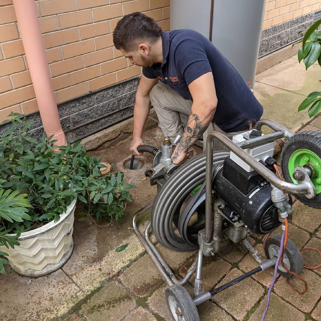 plumber clearing blocked drain with a snake