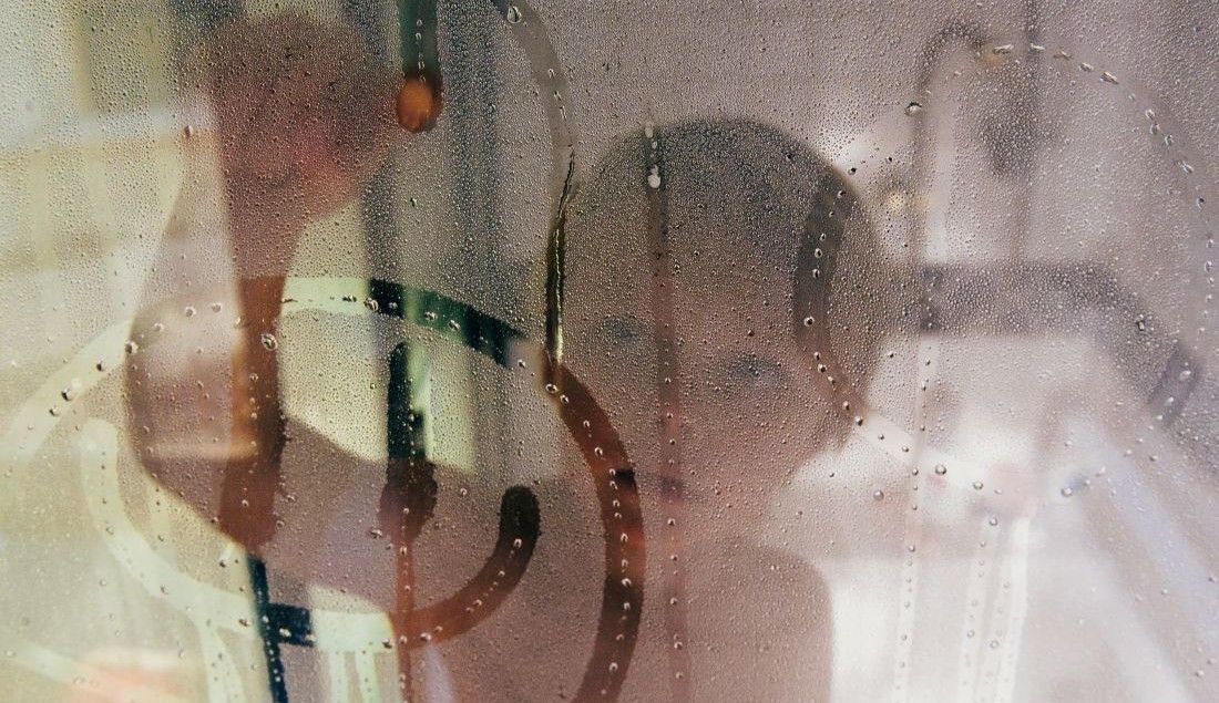 kid drawing on shower glass in a steamy bathroom