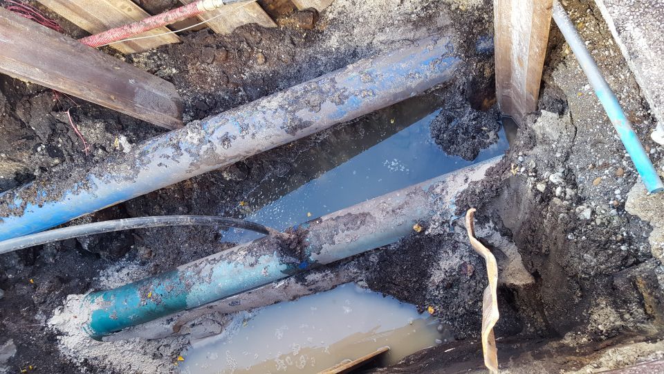 Pipes in an excavated area with surrounding dirt and water