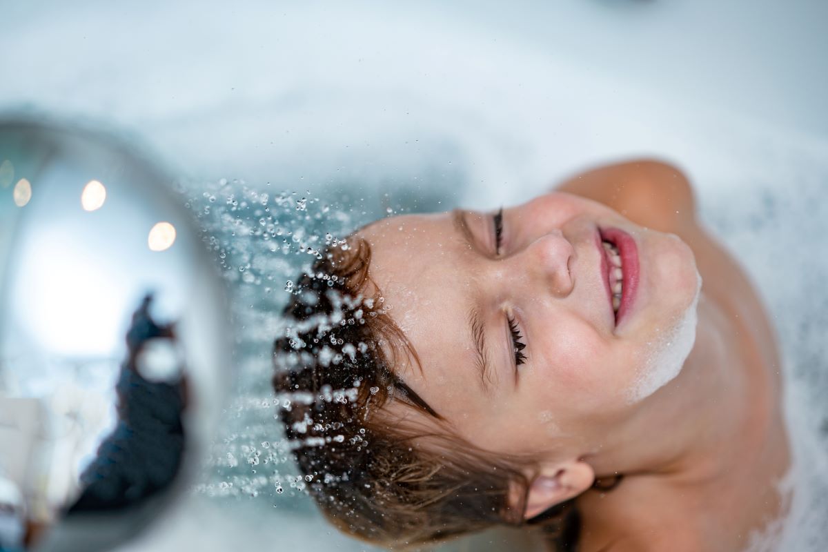 a young boy is taking a shower in a bathtub - tempering valve mixes the hot and cold water to prevent scalding