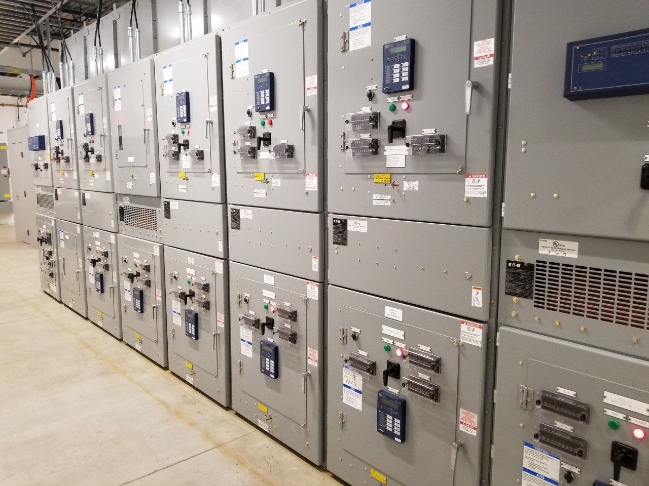Rows of gray electrical switchgear cabinets in a utility room.