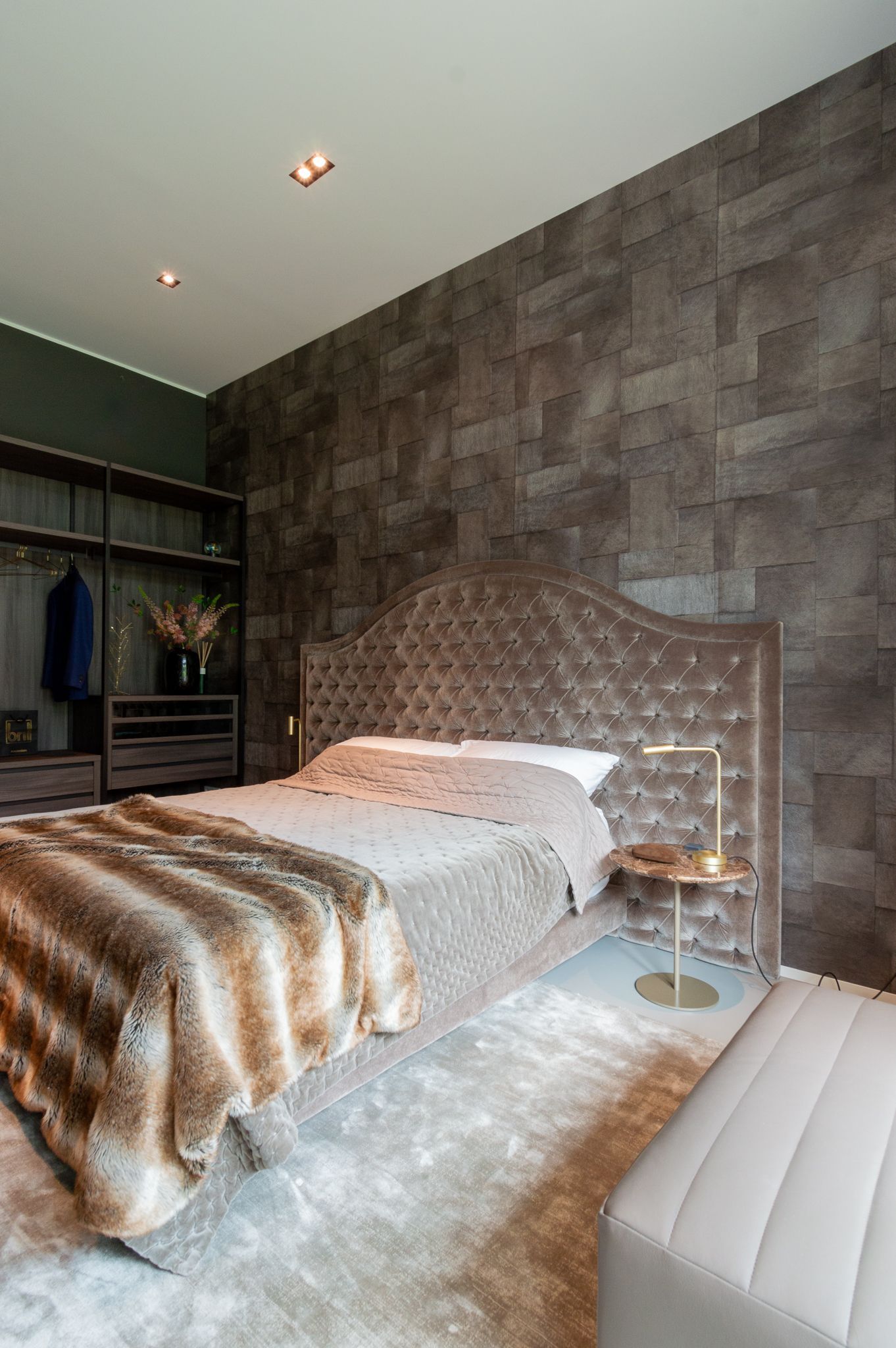 Een slaapkamer met een bed, nachtkastje, kleed en inloopkast.