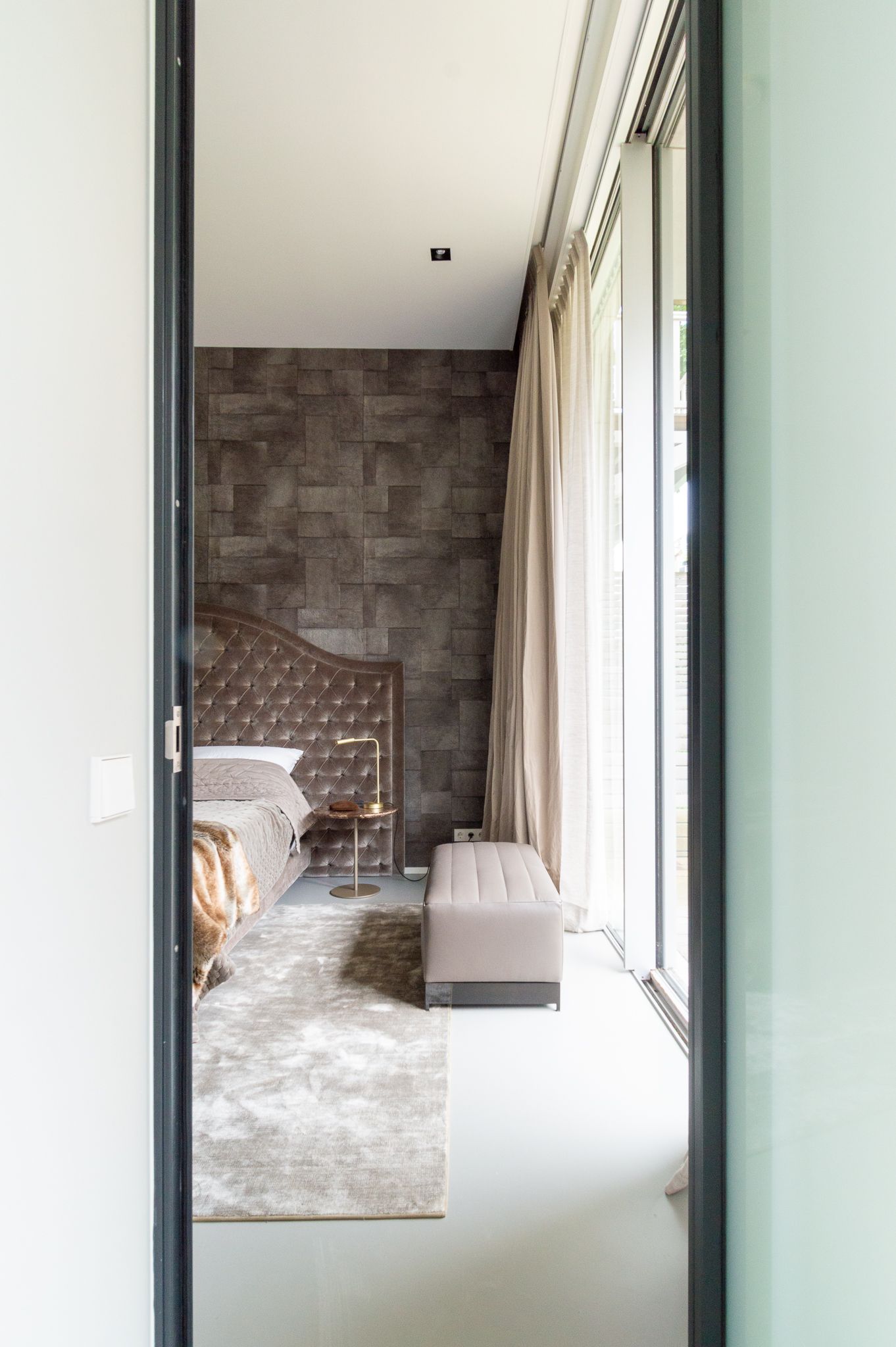 Een deur die leidt naar een slaapkamer met een groot raam.