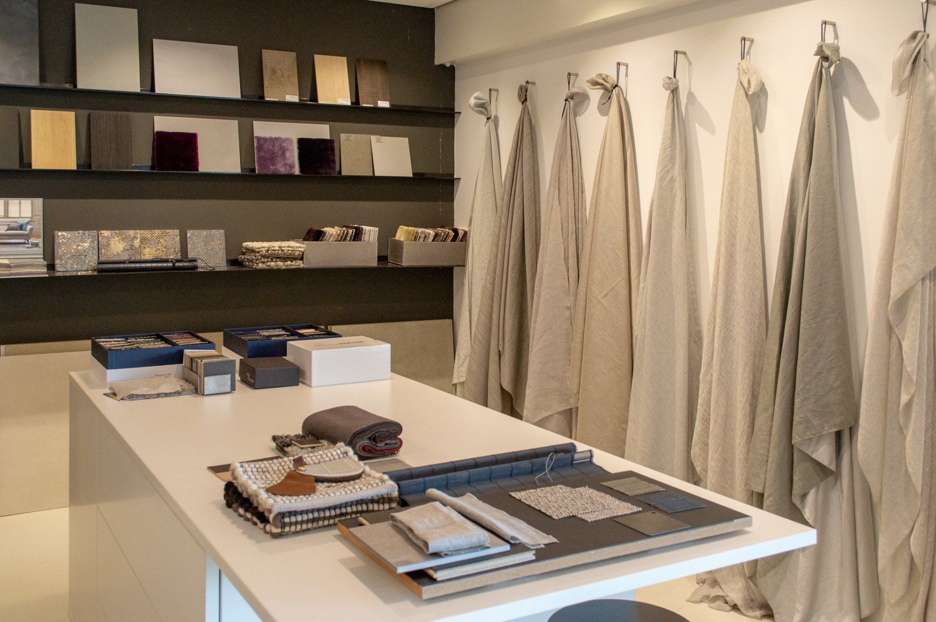 Een materialen tafel in een showroom met linnen gordijnen aan de muur