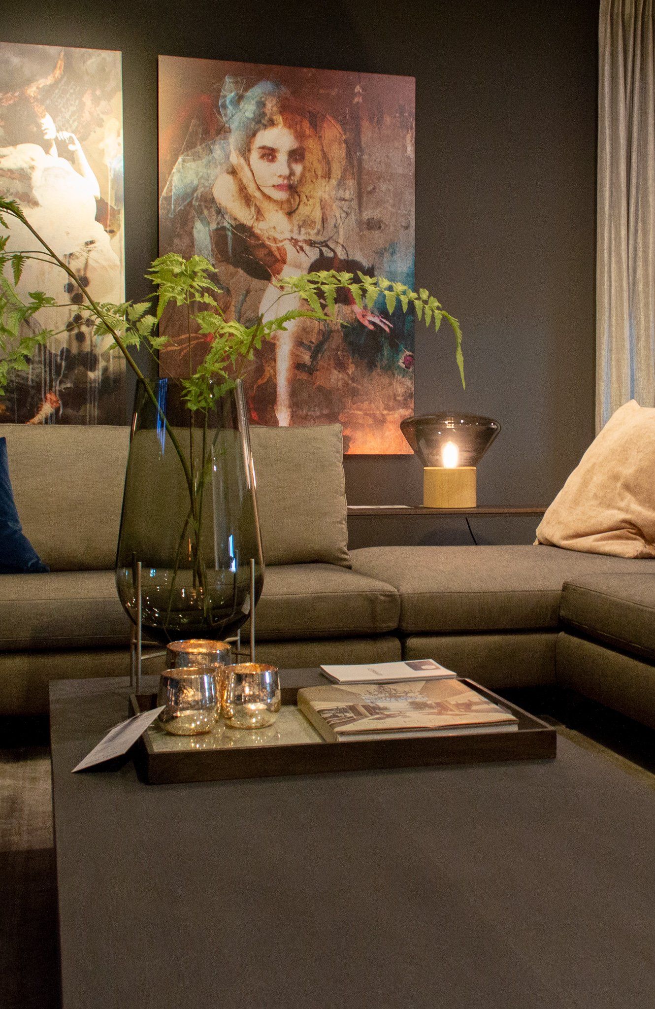 Een woonkamer met een bank van Vibieffe, salontafel van Keijser&Co, kaarsen en een schilderij aan de muur.