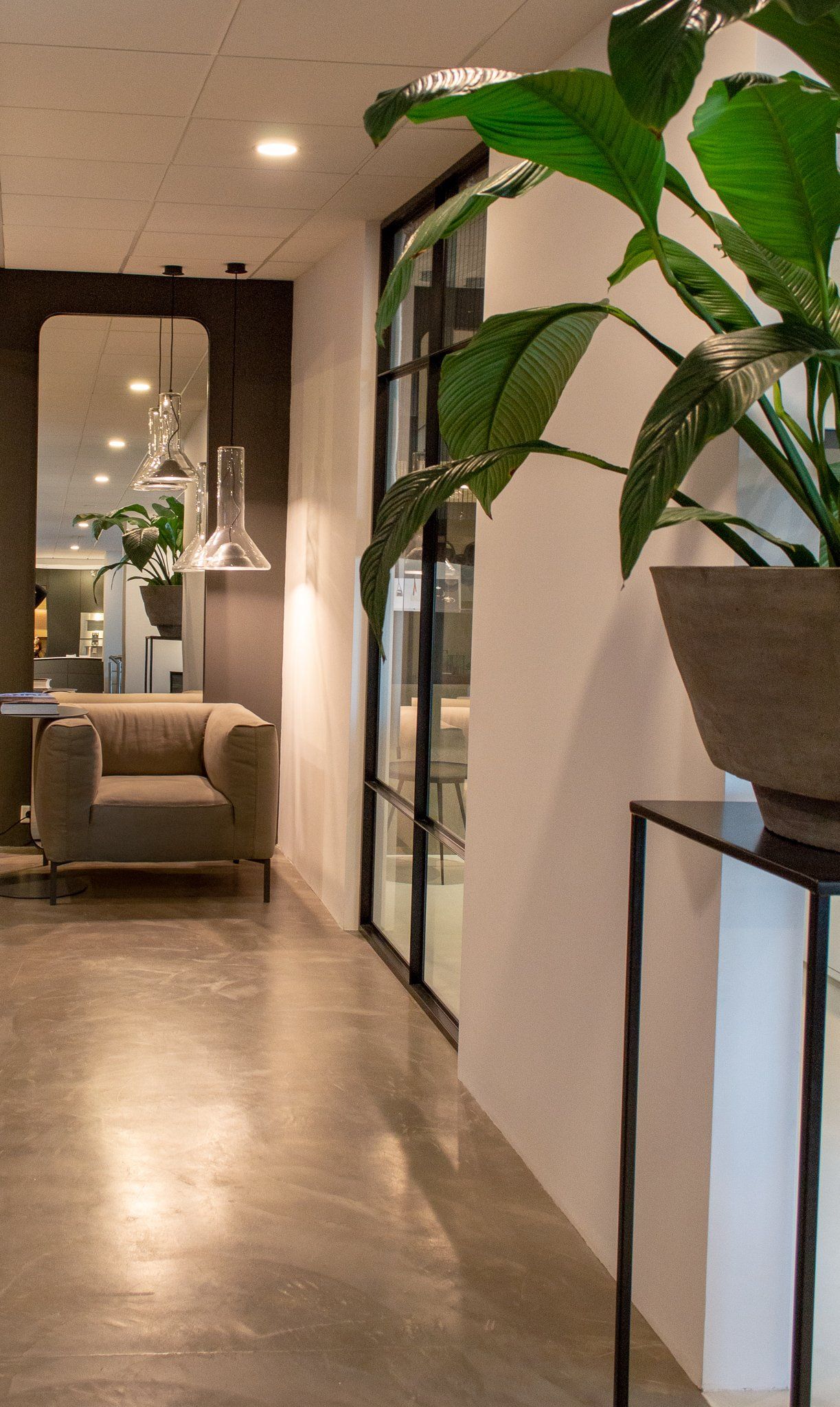 Een gang met een stoel, tafel, spiegel van Cattelan Italia en potplant.