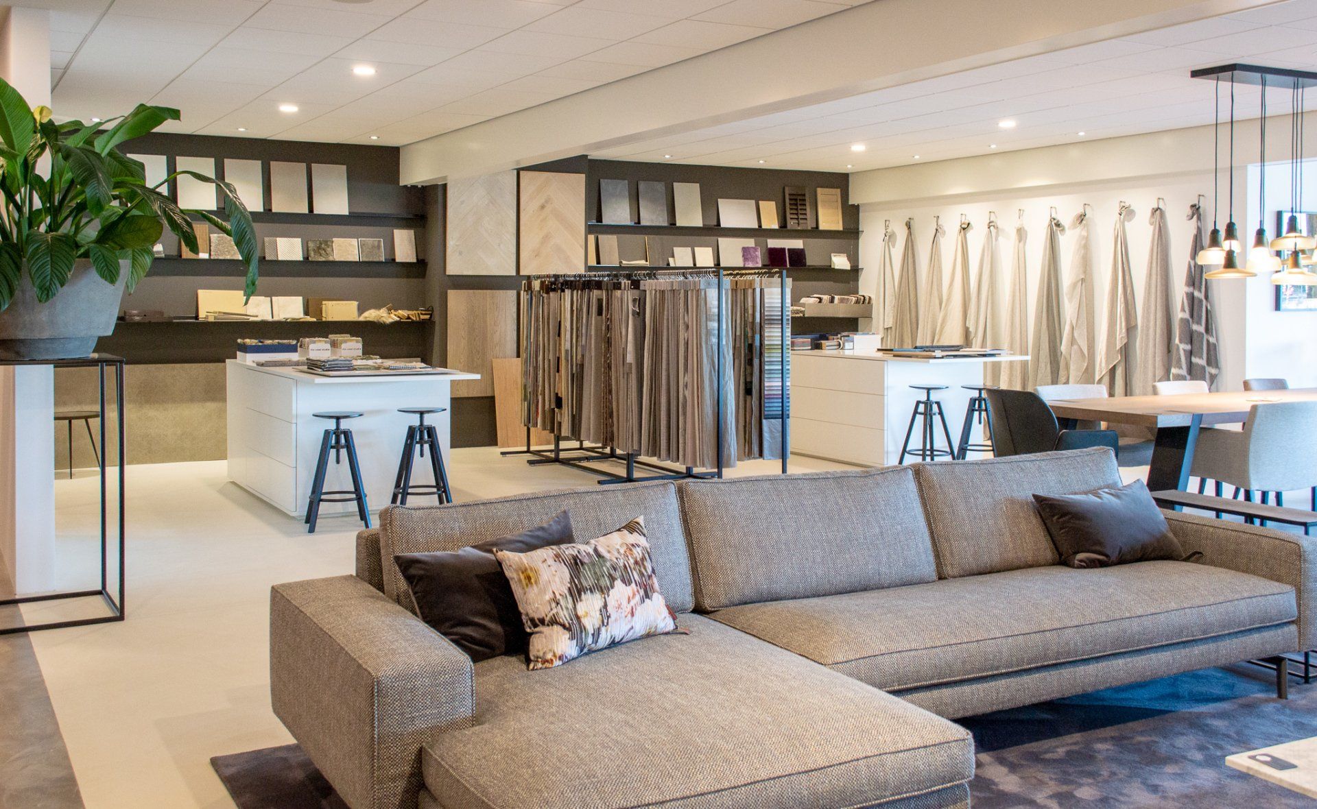 Een woonkamer met een bank en een tafel erin en op de achtergrond een collectie met natuurlijke en warme materialen.