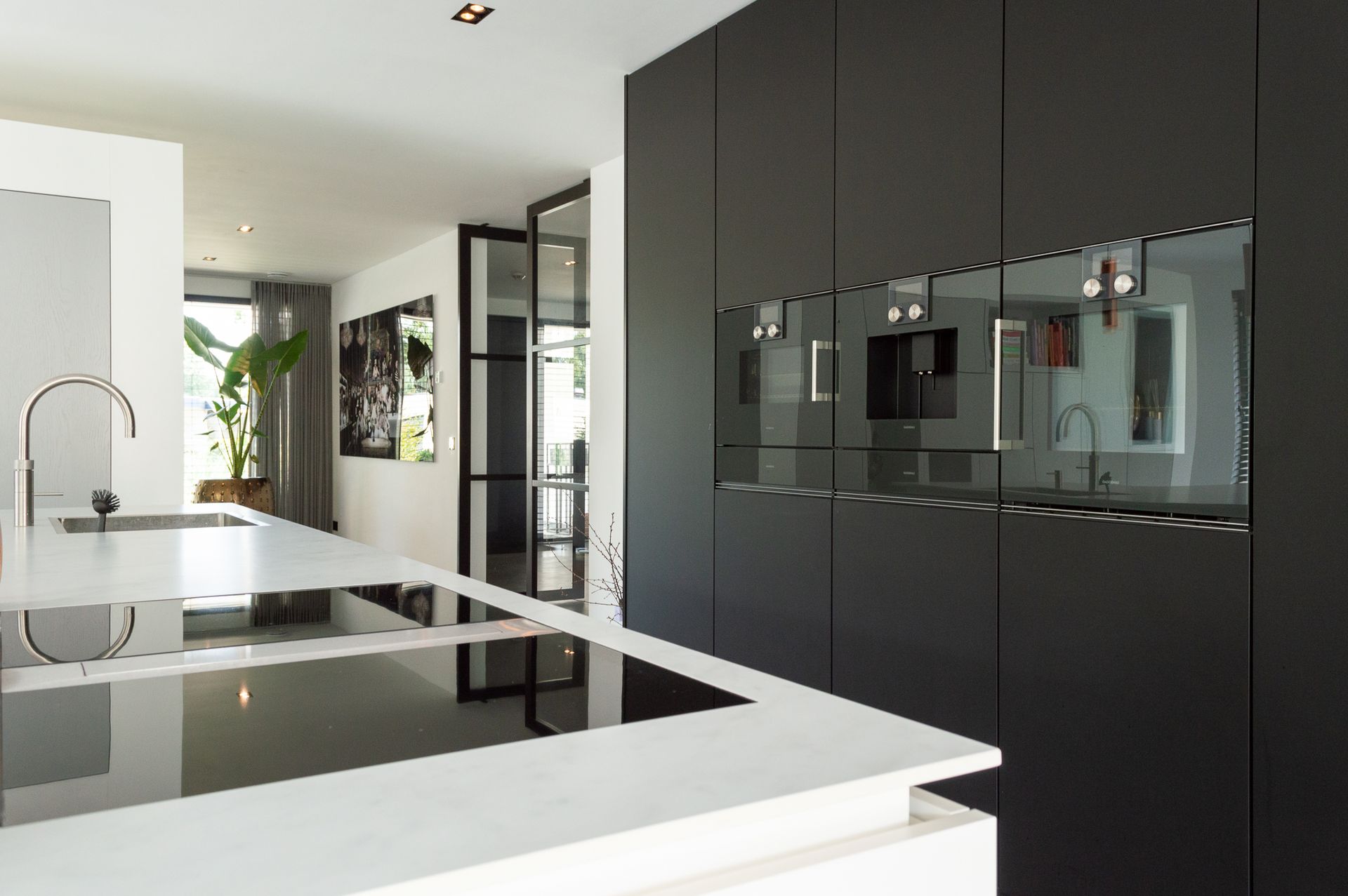 Een keuken met zwarte kasten en witte aanrechtbladen van De Mulder Keukens