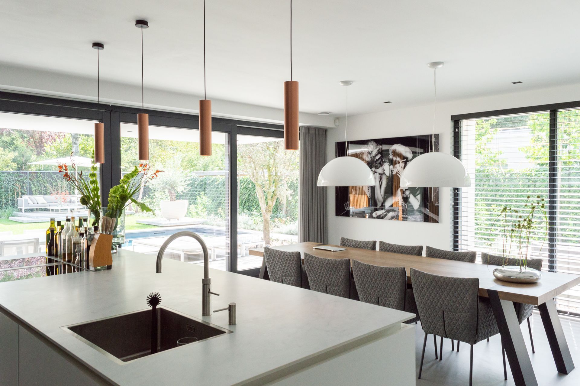 Een keuken met een spoelbak, eettafel van Qliv en stoelen van Label van de Berg.