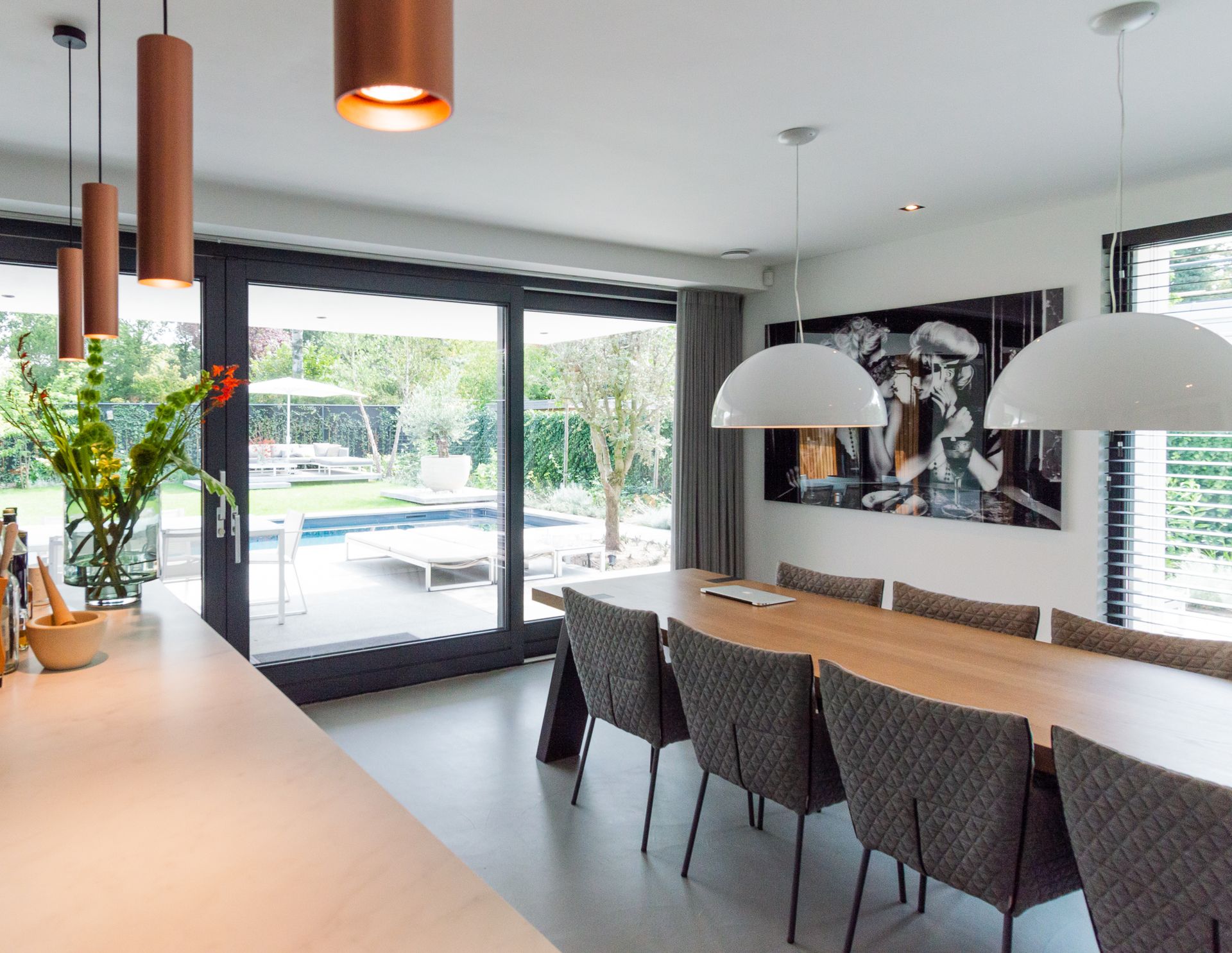Een eetkamer met een lange tafel van Van Seuren, stoelen van Label en een groot raam.
