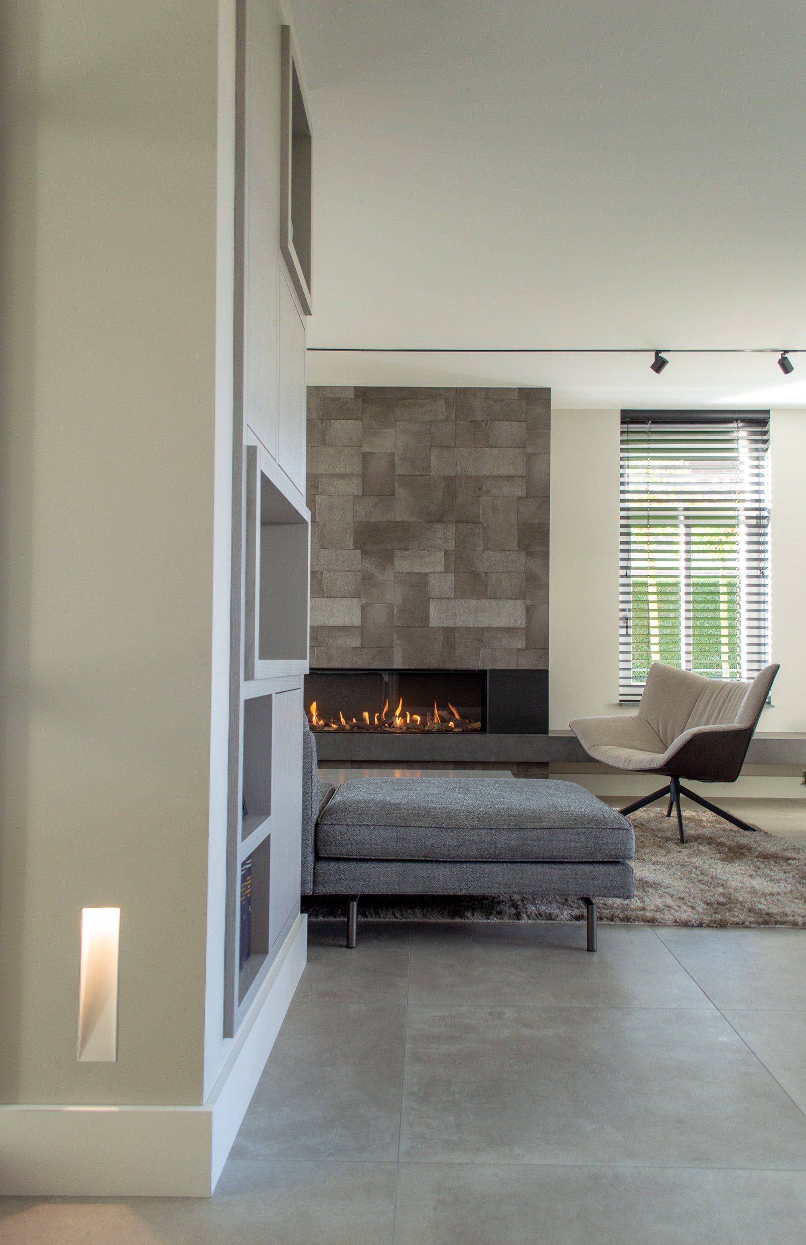 Een woonkamer met open haard, bank, stoel en kleed.