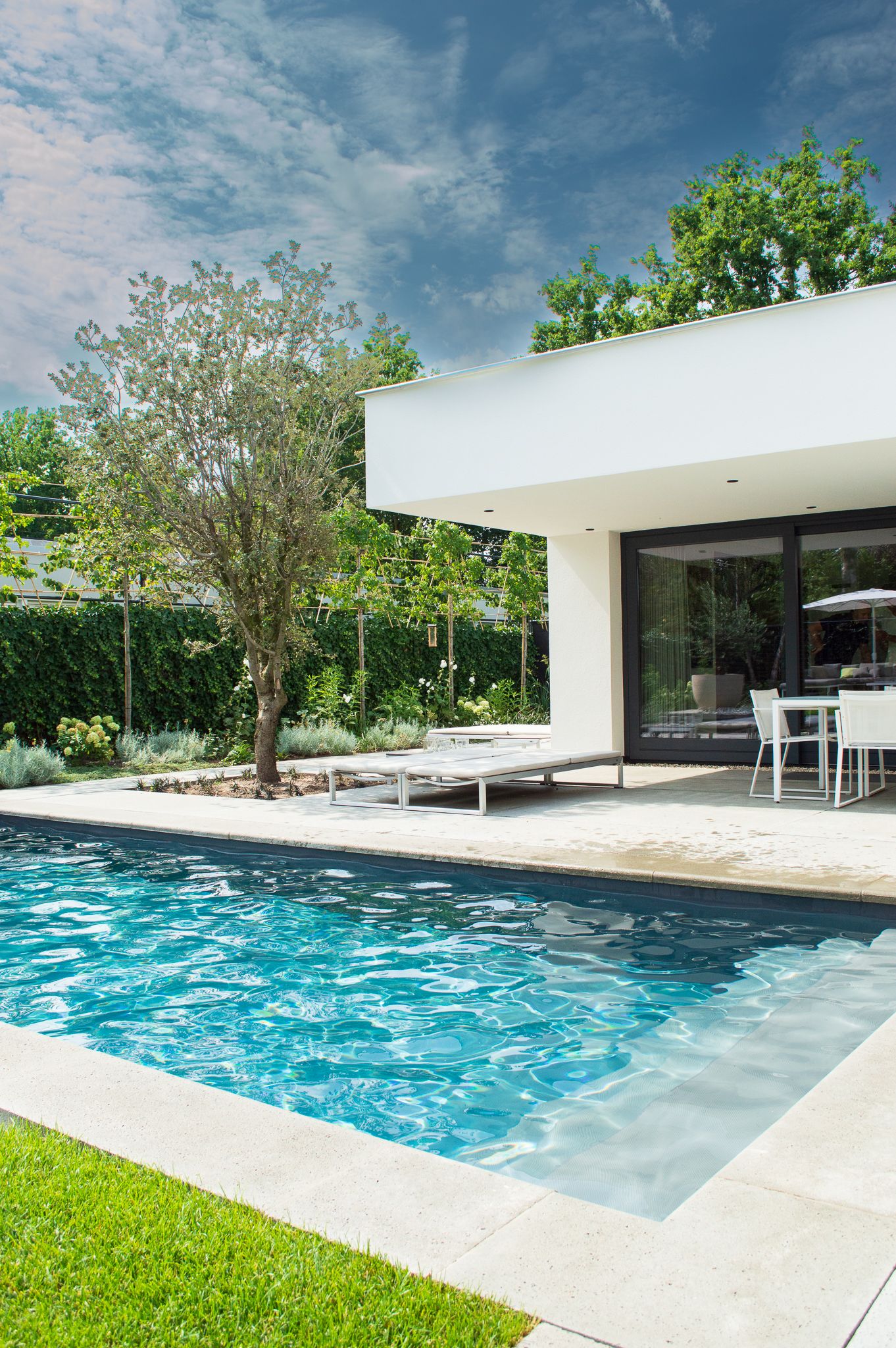 Een wit huis met een groot zwembad ervoor