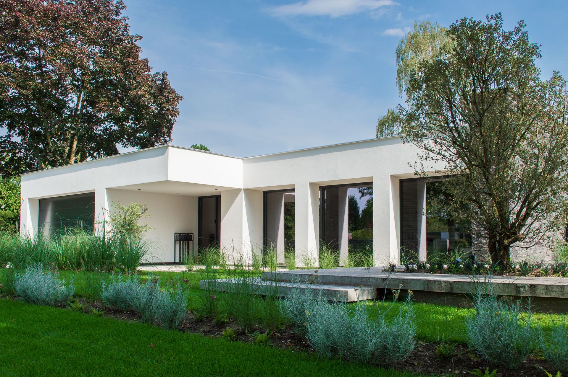 Een wit huis met veel ramen en bomen ervoor