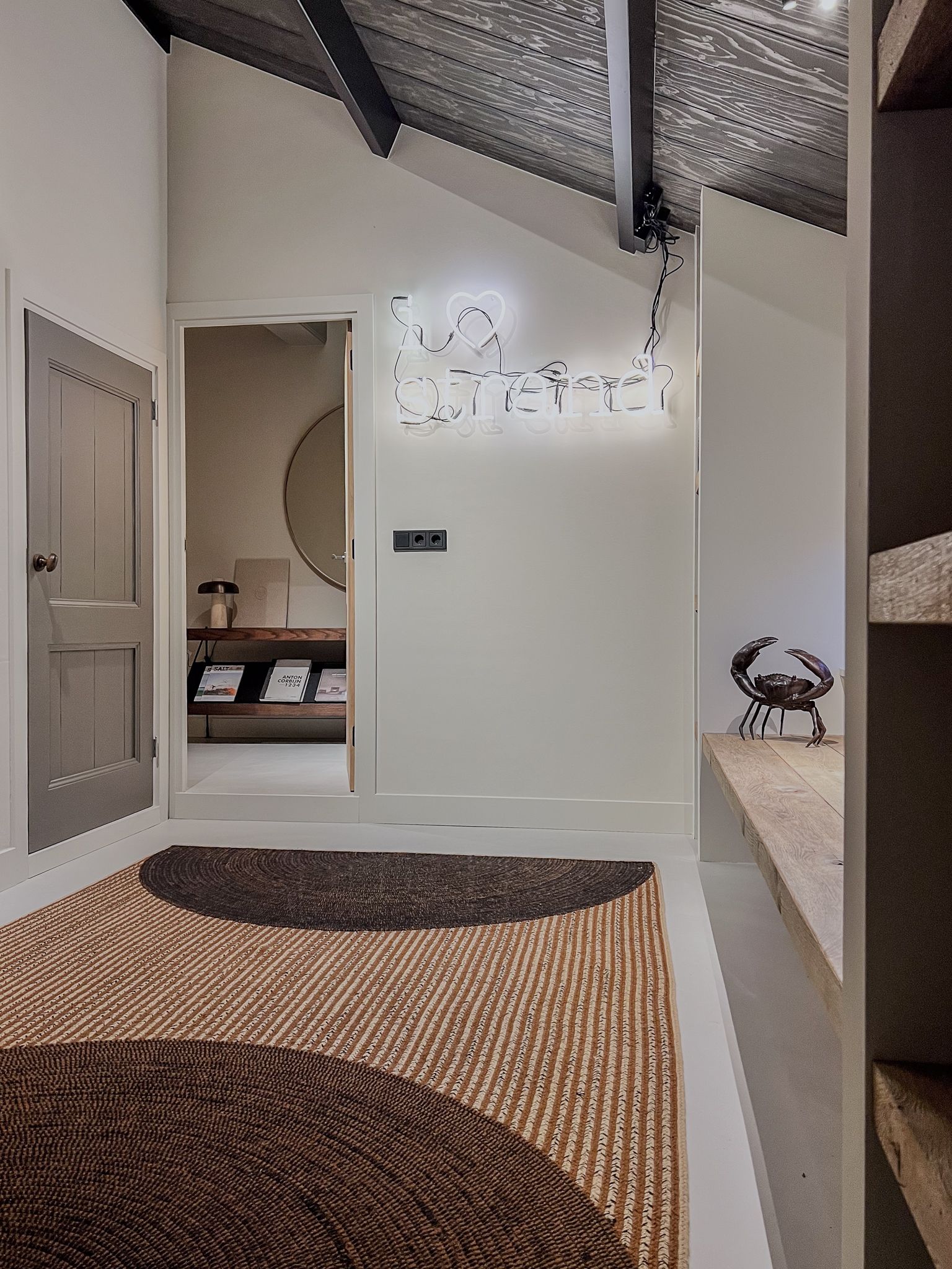 Een gang met een kleed van Elitis op de vloer en een deur die naar de opkamer leidt.