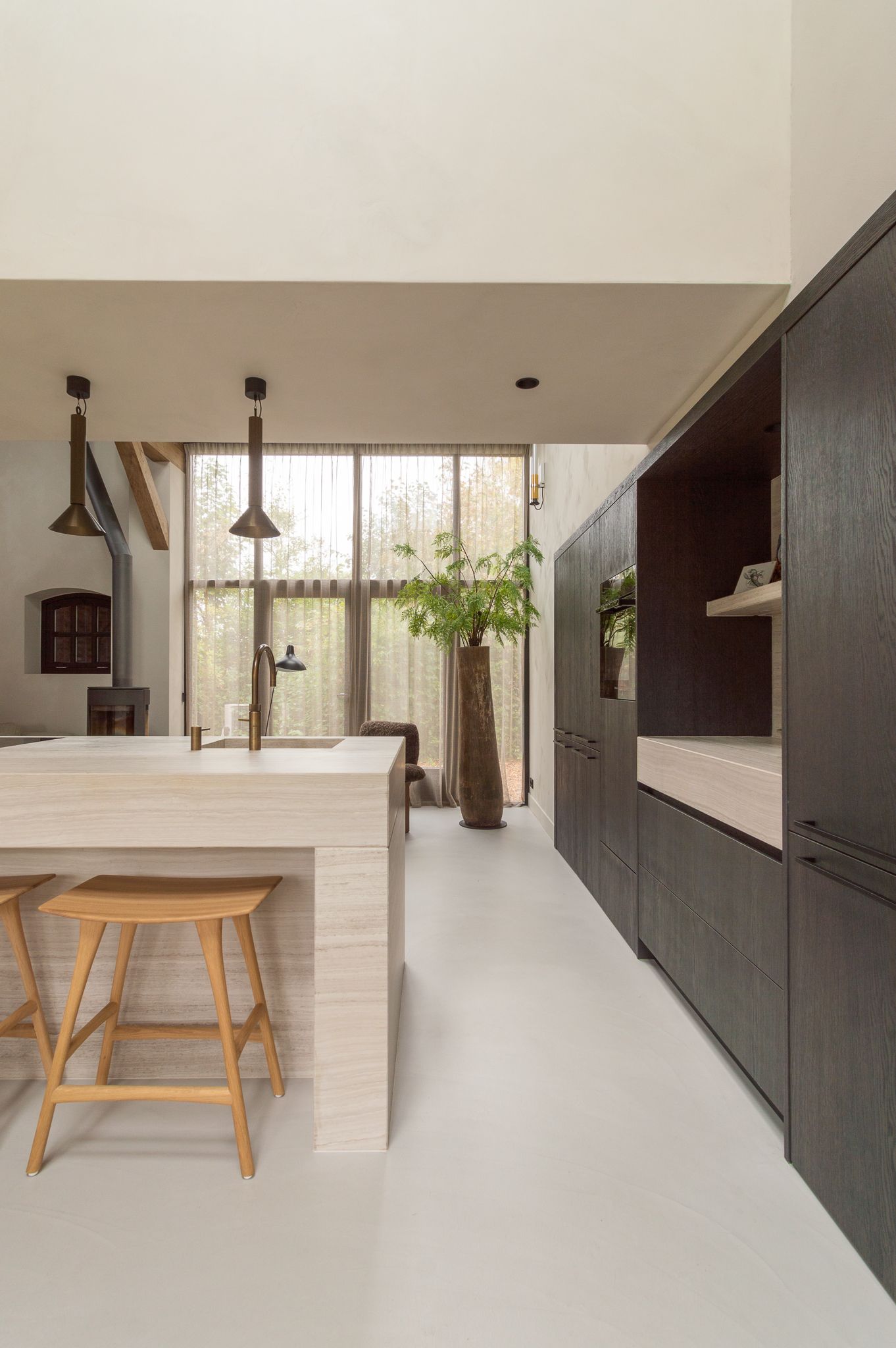 Een keuken met een groot kookeiland met marmeren blad en houten krukken van Ethnicraft