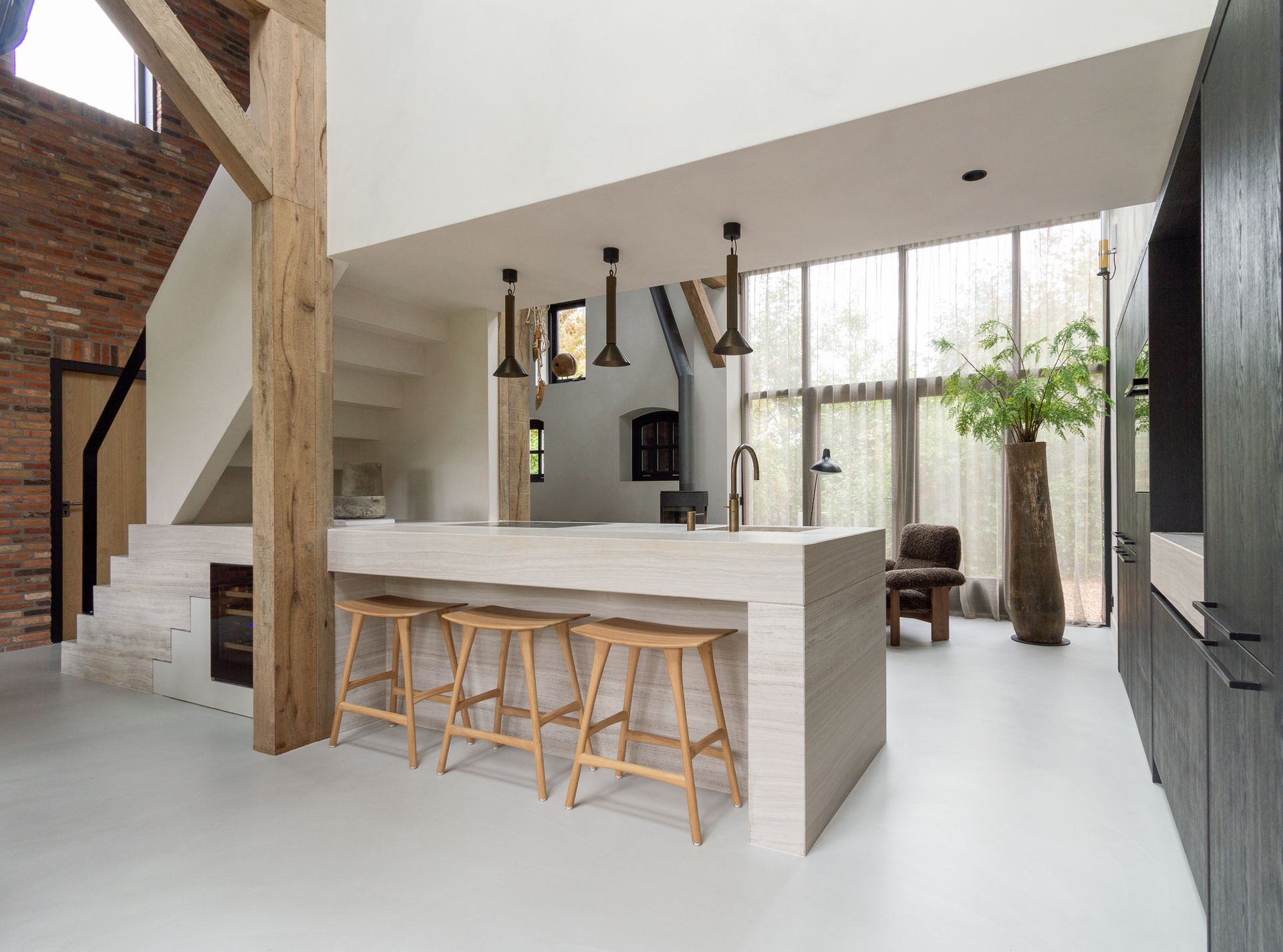 Een keuken met een groot kookeiland en houten krukken.Uit The Art of Living.