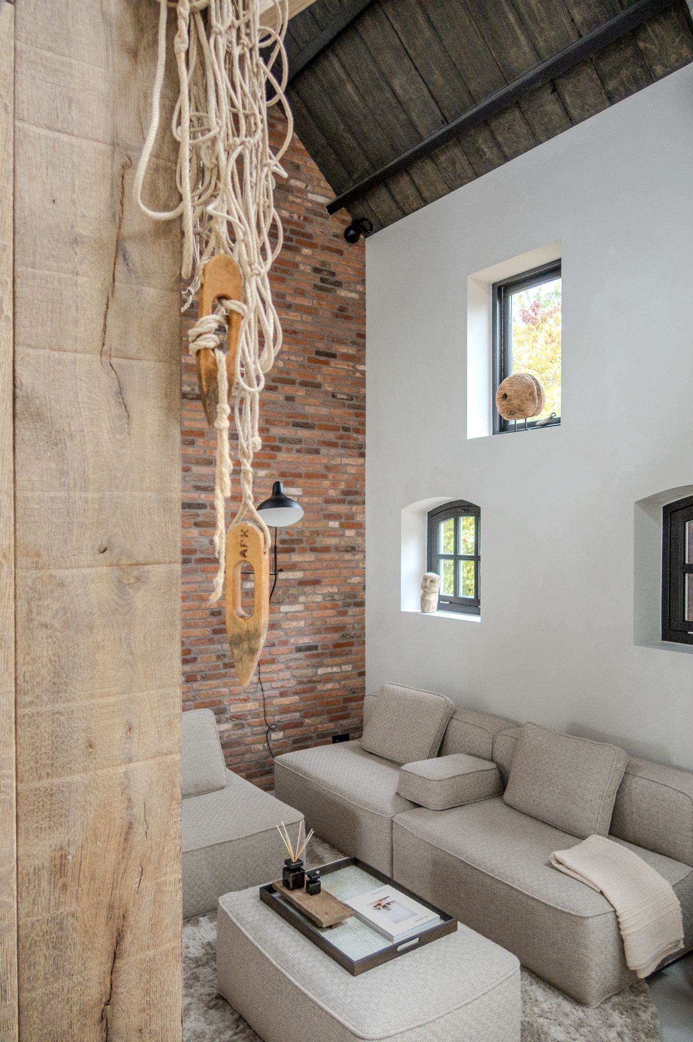 Een woonkamer met een bank, stoel, salontafel en bakstenen muur.