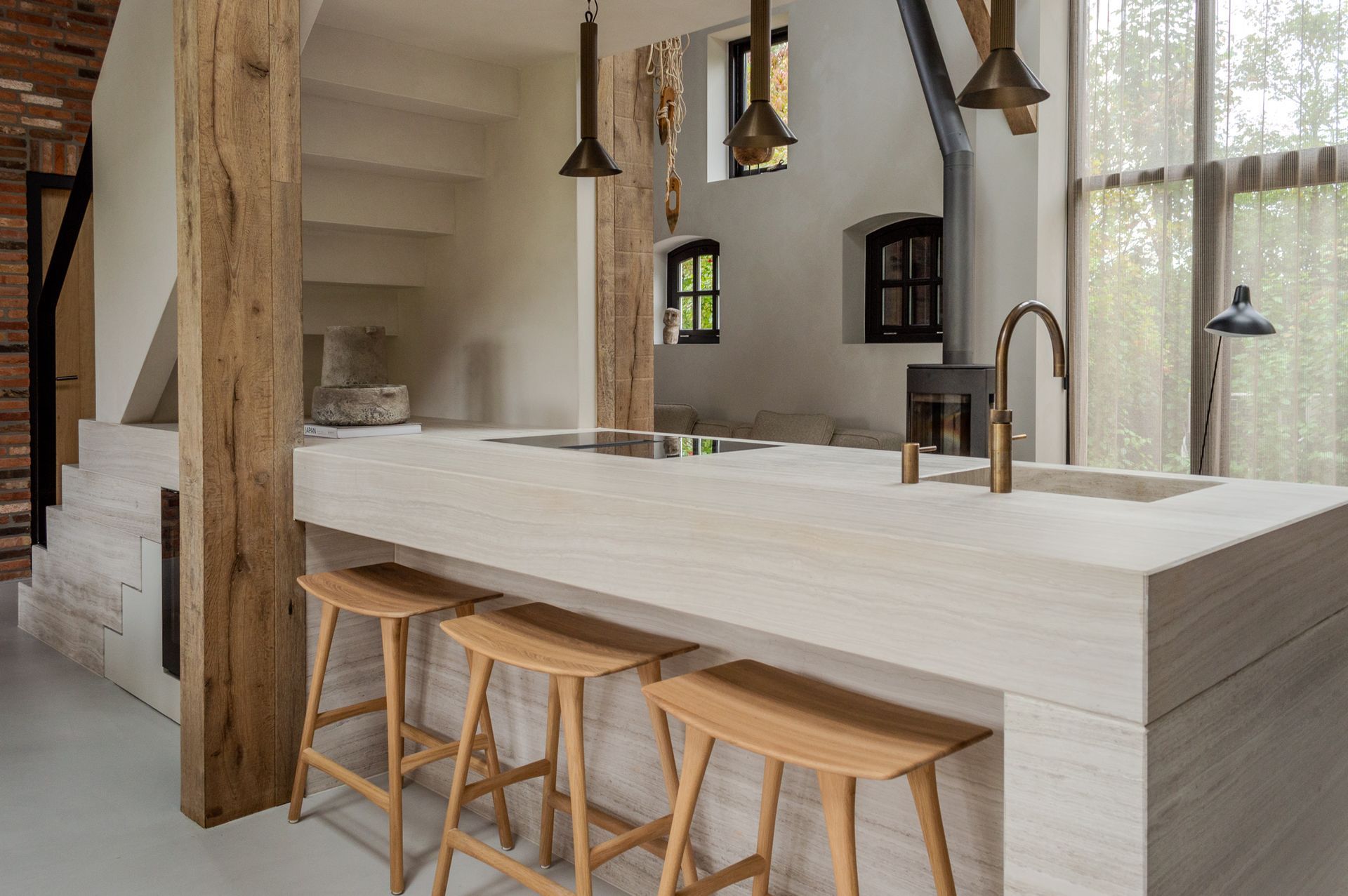 Een keuken met een groot kookeiland dat overloopt in de trap en houten krukken.