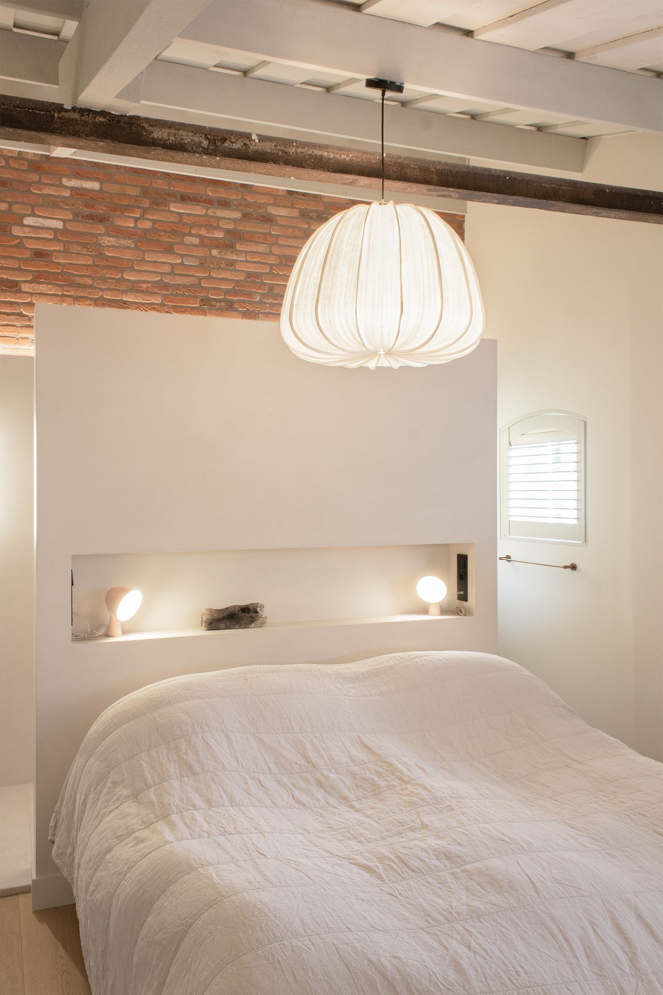 Een slaapkamer met een bed en een lamp van Ay Illuminate aan het plafond.