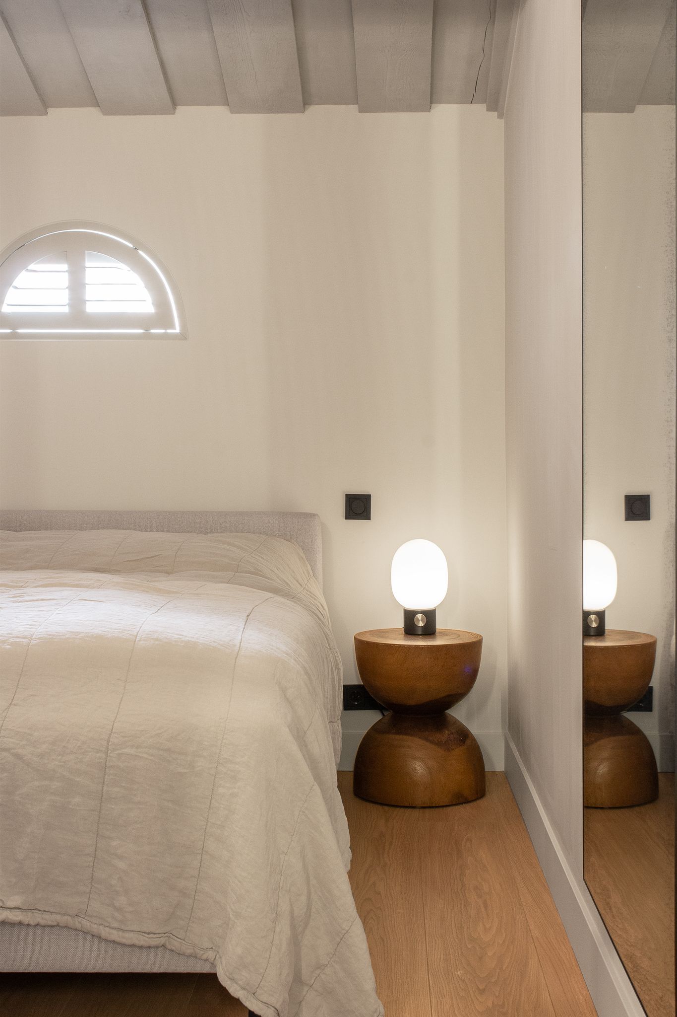 Een slaapkamer met een bed, twee nachtkastjes en een spiegel.