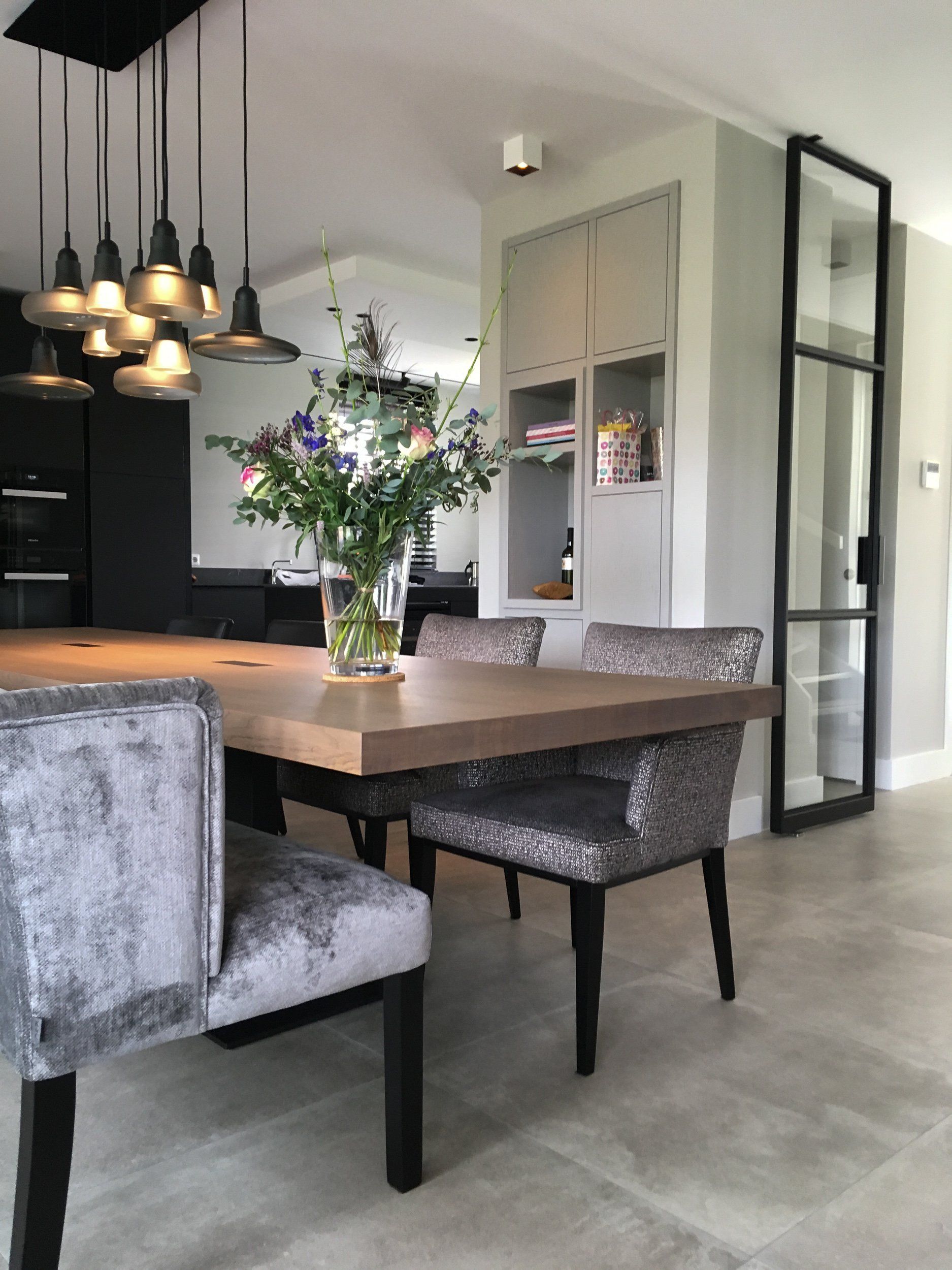 Een eettafel met stoelen en een vaas met bloemen erop