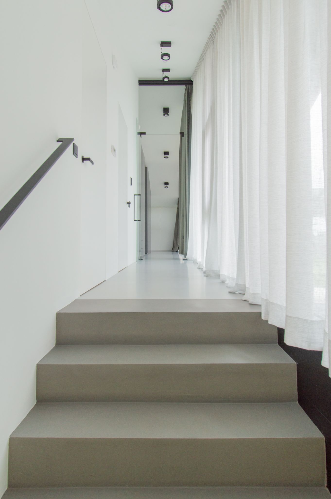 Een lange gang met een trap die naar de tweede verdieping leidt